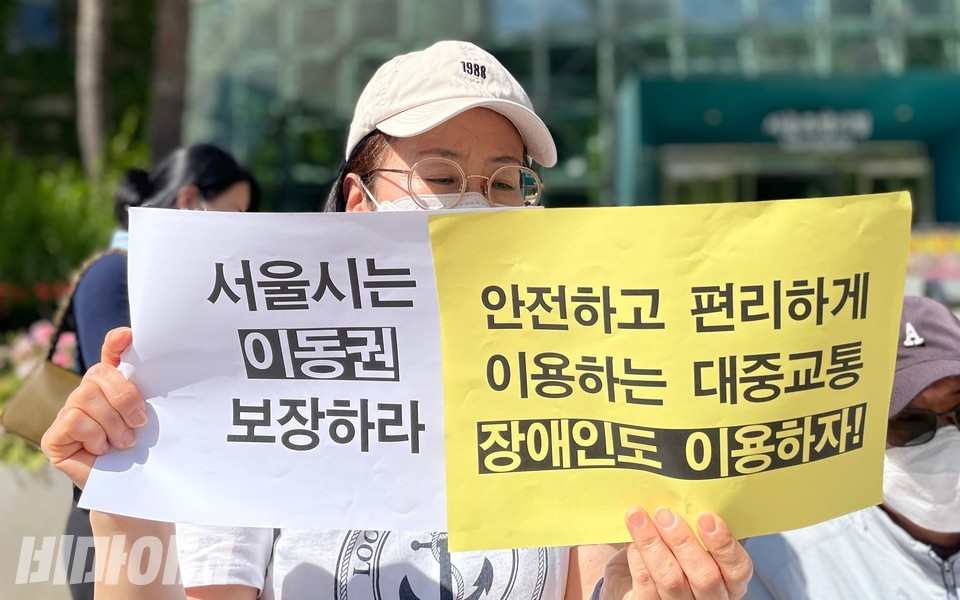 기자회견 참가자가 “서울시는 이동권 보장하라. 안전하고 편리하게 이용하는 대중교통, 장애인도 이용하자!”라고 적힌 피켓을 양손에 들고 있다. 사진 하민지