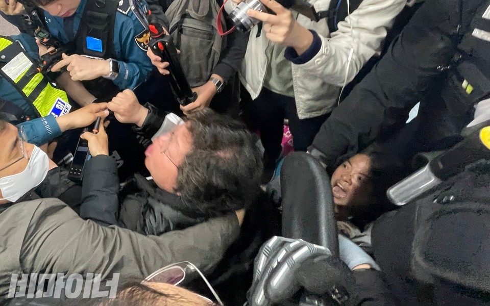 이형숙 서울시장애인자립생활센터협의회 회장과 문애린 이음장애인자립생활센터 소장이 서울교통공사의 폭력을 당하고 있다. 공사 직원은 두 사람의 휠체어를 강제로 끌어냈다. 이 때문에 문 소장이 휠체어에서 분리됐다. 문 소장은 이 회장 뒤에서 바닥에 주저앉아 공사를 규탄하는 중이다. 사진 하민지