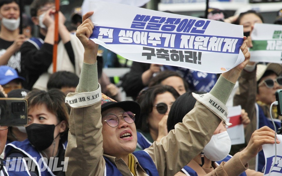 한 부모연대 회원이 “발달장애인 전 생애주기 지원체계 구축하라”라고 적힌 현수막을 높이 들어보이고 있다. 사진 하민지