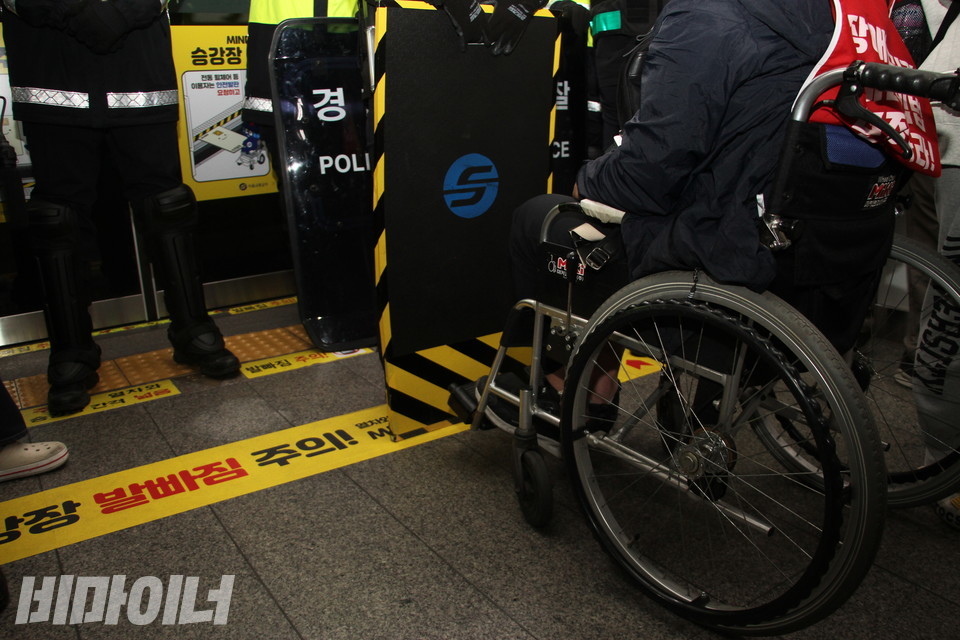 21일 오전 서울지하철 4호선 회현역 승강장에서 경찰과 서울교통공사가 각각 방패와 이동식 안전발판을 세워 들고 휠체어 탄 활동가의 탑승을 막아서고 있다. 사진 하민지