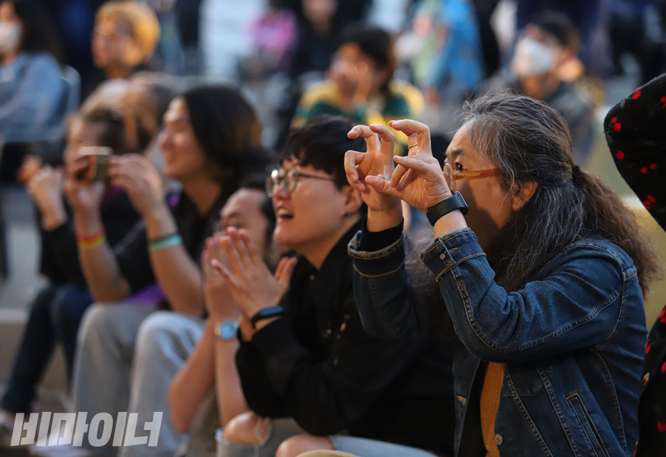 27일 오후 6시 서울 대학로 마로니에공원 야외무대에서 가수 이랑이 ‘늑대가 나타났다’를 부르자 수리야 경기장애인차별철폐연대 집행위원장(맨 오른쪽)이 두 손으로 갈퀴 모양을 만들어 보이고 있다. 사진 복건우