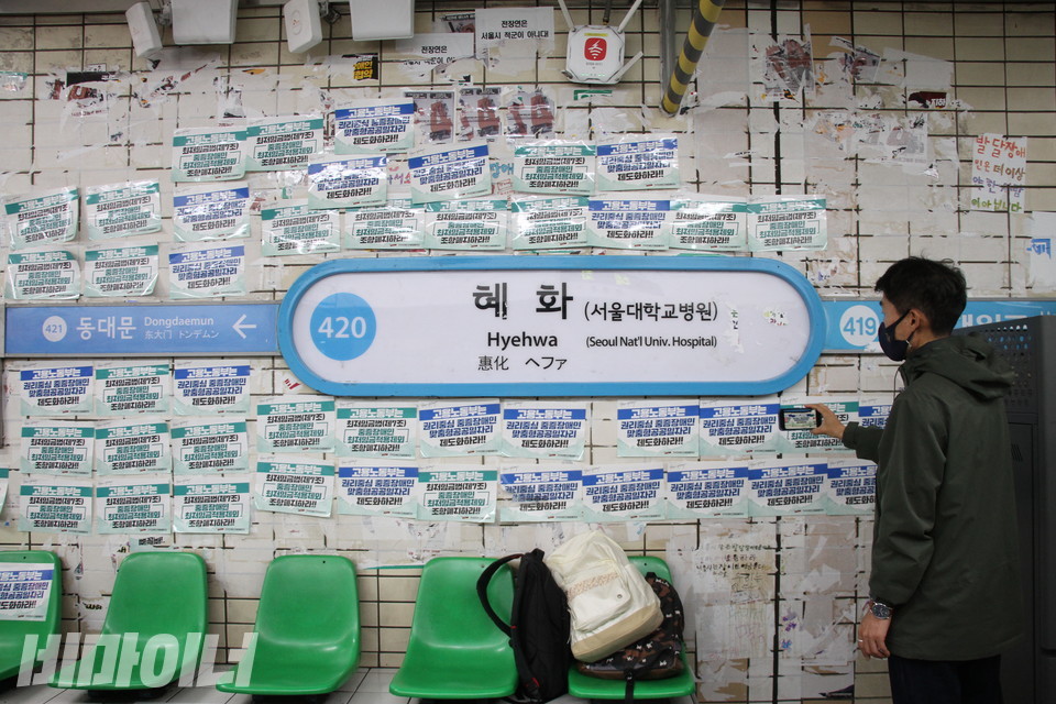 이영욱 전장야협 영상활동가가 스티커가 가득 채워진 혜화역 승강장 벽면을 핸드폰으로 촬영하고 있다. 사진 강혜민