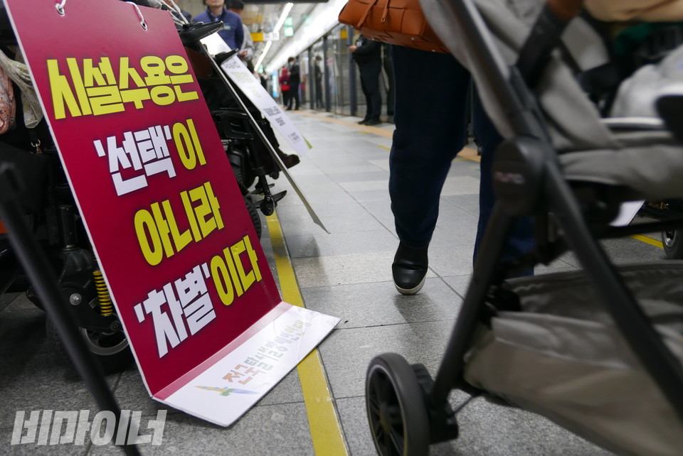 “시설 수용은 선택이 아니라 차별이다”라는 피켓이 보이고, 그 옆을 어떤 한 사람이 유아차를 몰고 지나간다. 사진 양유진