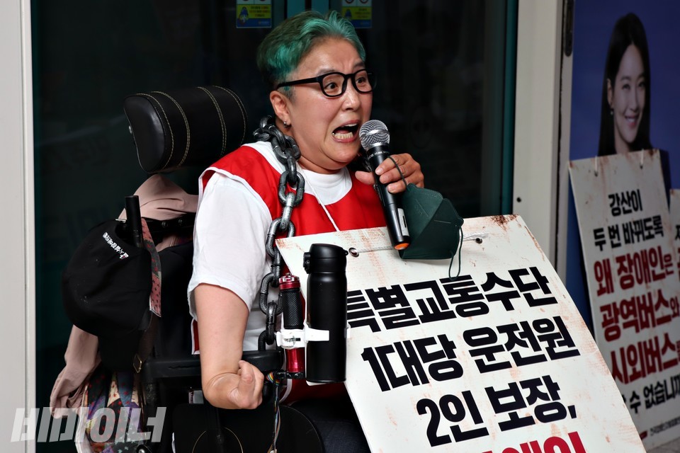 문경희 세종장애인차별철폐연대 대표가 발언 중이다. 그는 “특별교통수단 1대당 운전원 2인 보장”이라고 적힌 피켓을 목에 걸었다. 사진 하민지