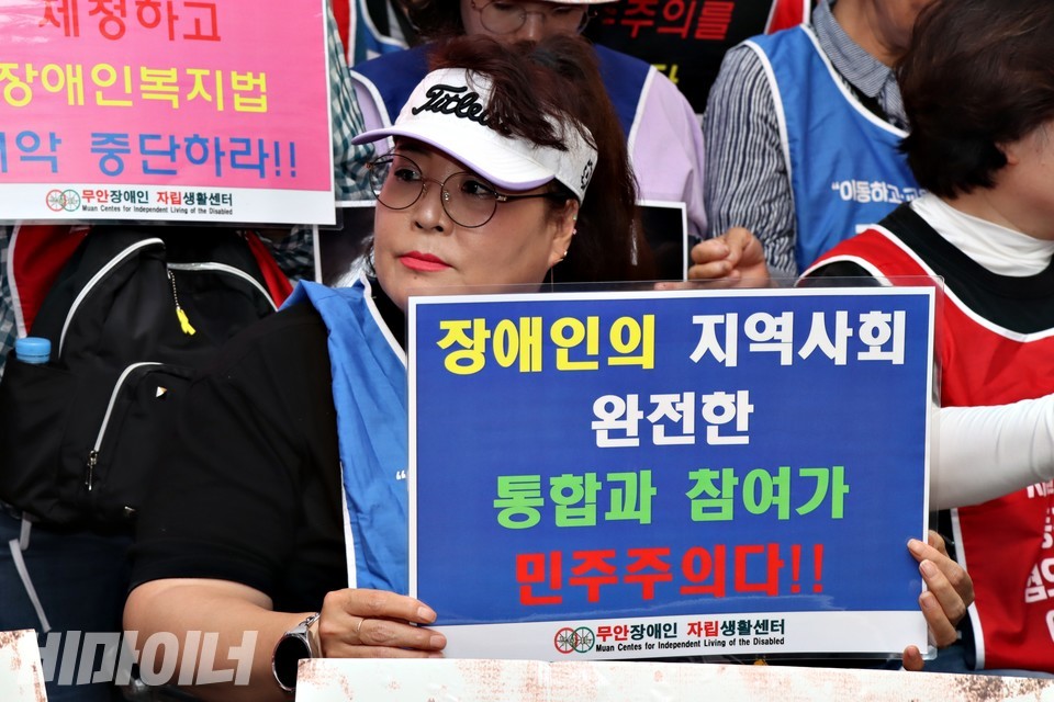무안장애인자립생활센터 활동가가 “장애인의 지역사회 완전한 통합과 참여가 민주주의다”라고 적힌 피켓을 들고 있다. 사진 하민지