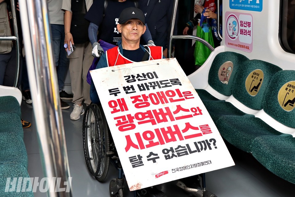한 휠체어 이용 활동가가 광주송정역에서 지하철에 탑승하고 있다. 그는 “강산이 두 번 바뀌도록 왜 장애인은 광역버스와 시외버스를 탈 수 없습니까?”라고 적힌 피켓을 목에 걸었다. 이날 휠체어 이용자 70여 명이 열차에 타는 데 약 11분이 소요됐다. 사진 하민지