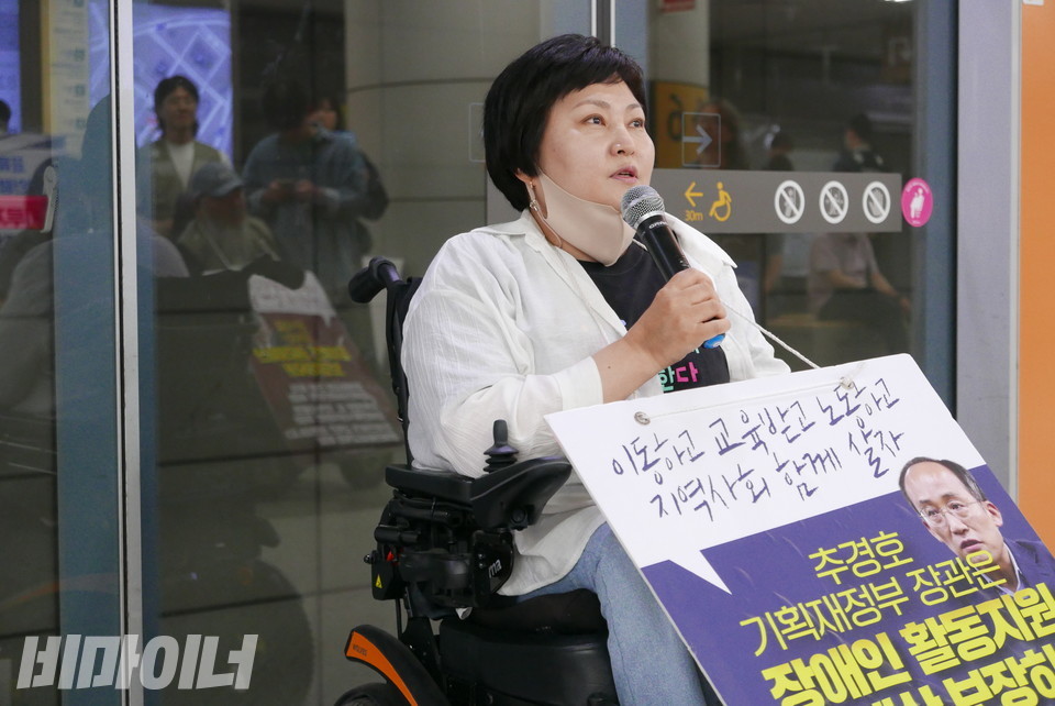 조은상 상록수장애인자립생활센터 소장이 국회의사당역 선전전에서 “이동하고 교육받고 노동하고 지역사회 함께 살자”라고 적힌 피켓을 목에 걸고 발언 중이다. 사진 양유진