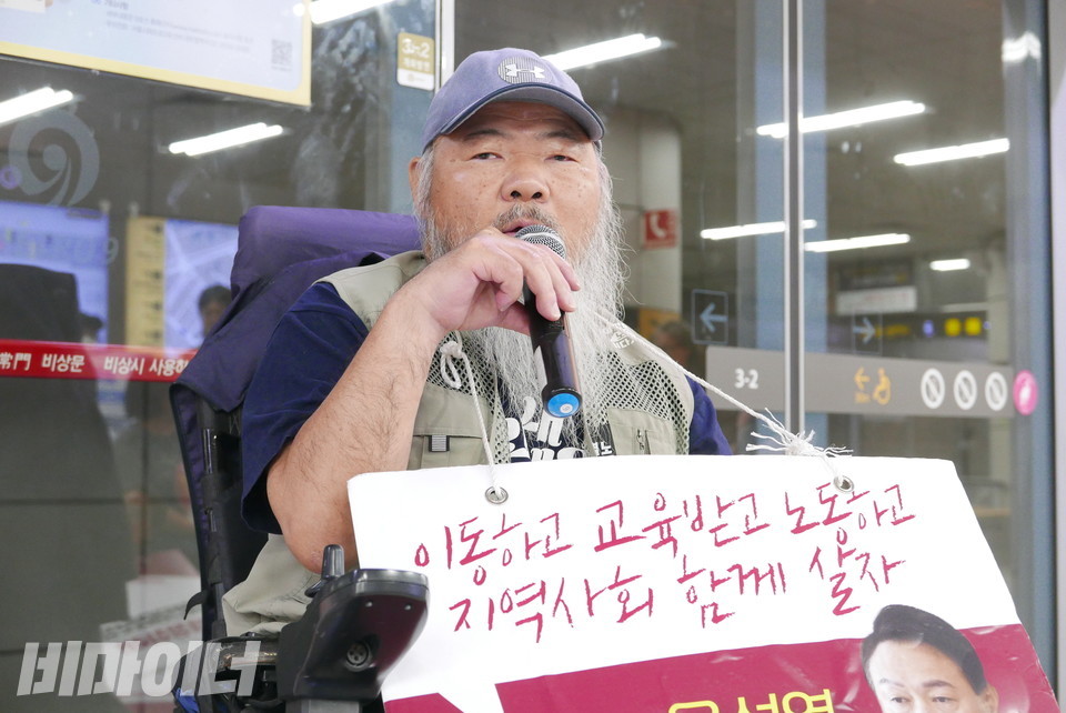 김명학 노들장애인야학 교장이 “이동하고 교육받고 노동하고 지역사회 함께 살자”라고 적힌 피켓을 목에 걸고 발언하고 있다. 사진 양유진