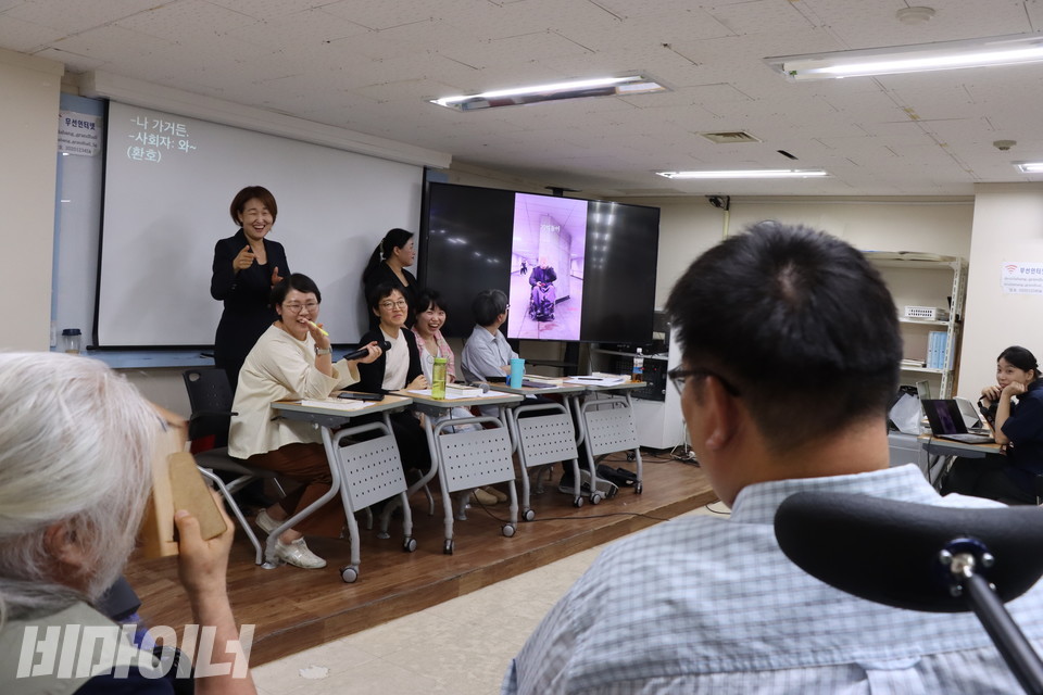 2부 시작 전 전사들의 노래 영상을 보며 크게 웃고 있다. 구술자들이 각자 자신의 인생 노래를 뽑아 부른 것으로, 이 영상은 비마이너 유튜브에 올라와 있다. 박경석 대표가 본인의 영상이 나오자 쑥쓰러워 하며 액자로 얼굴을 가리고 있다. 사진 이슬하