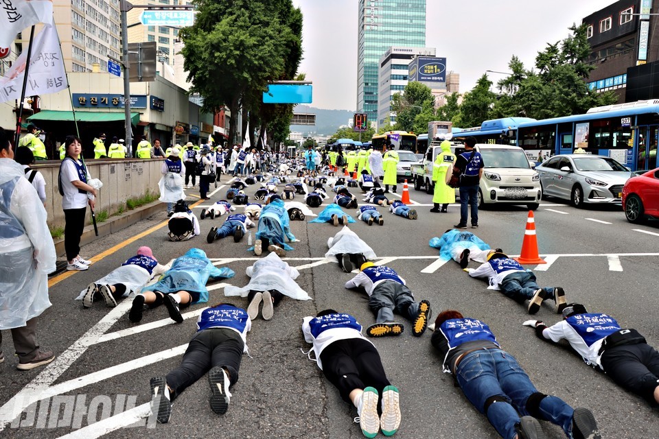 부모연대 오체투지 현장. 일부 활동가들이 우비를 입고 있다. 오체투지 대오 옆에 버스, 승용차, 택시 등이 지나가고 있다. 사진 하민지