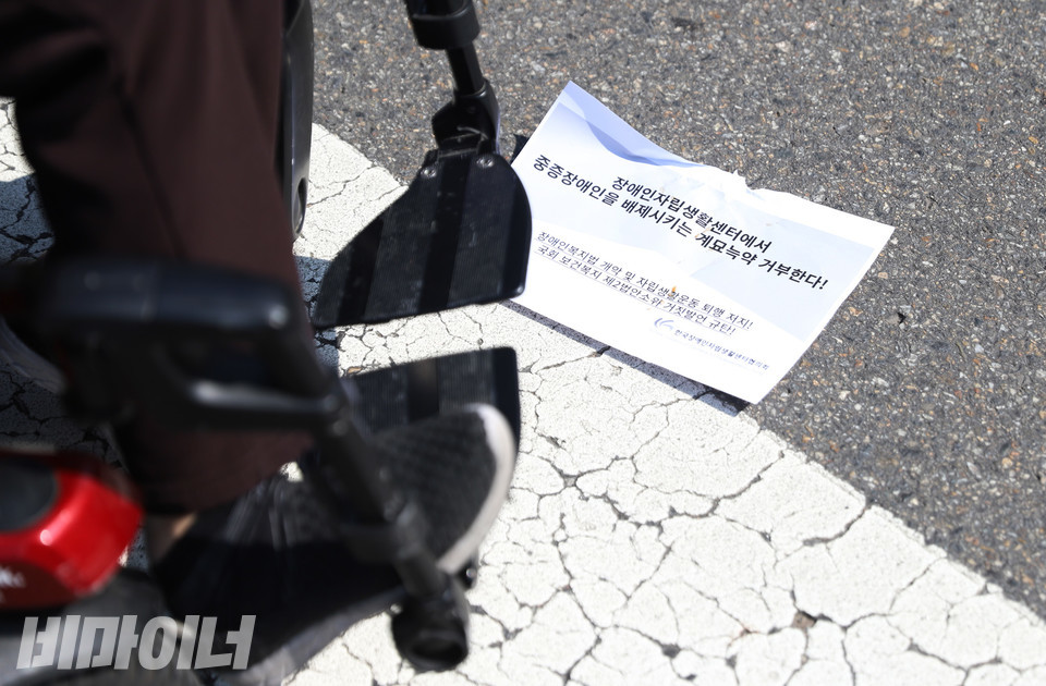 휠체어 옆 바닥에 “장애인자립생활센터에서 중증장애인을 배제시키는 계묘늑약 거부한다”고 적힌 종이가 떨어져 있다. 사진 강혜민