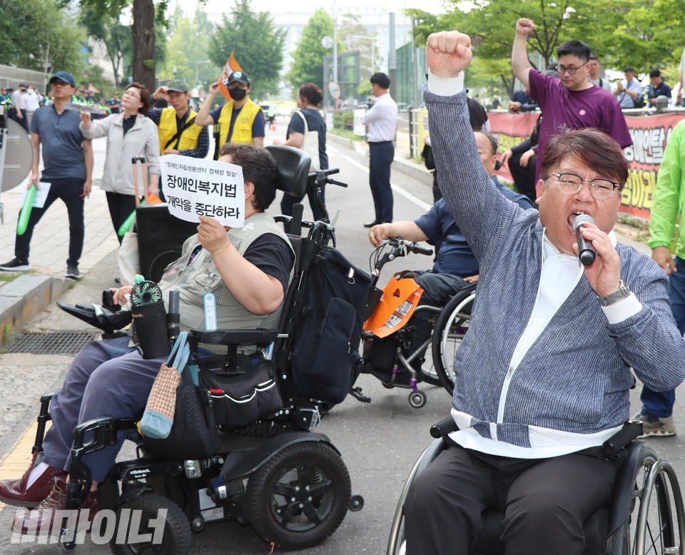 19일 오후 국회 앞. 진형식 한국장애인자립생활센터총연합회 회장(오른쪽)이 장애인복지법 개정안 제정을 촉구하며 구호를 외치고 있다. 그 뒤에서 이형숙 서울시장애인자립생활센터협의회 회장이 “장애인복지법 개악을 중단하라”고 적힌 피켓을 들고 있다. 사진 강혜민
