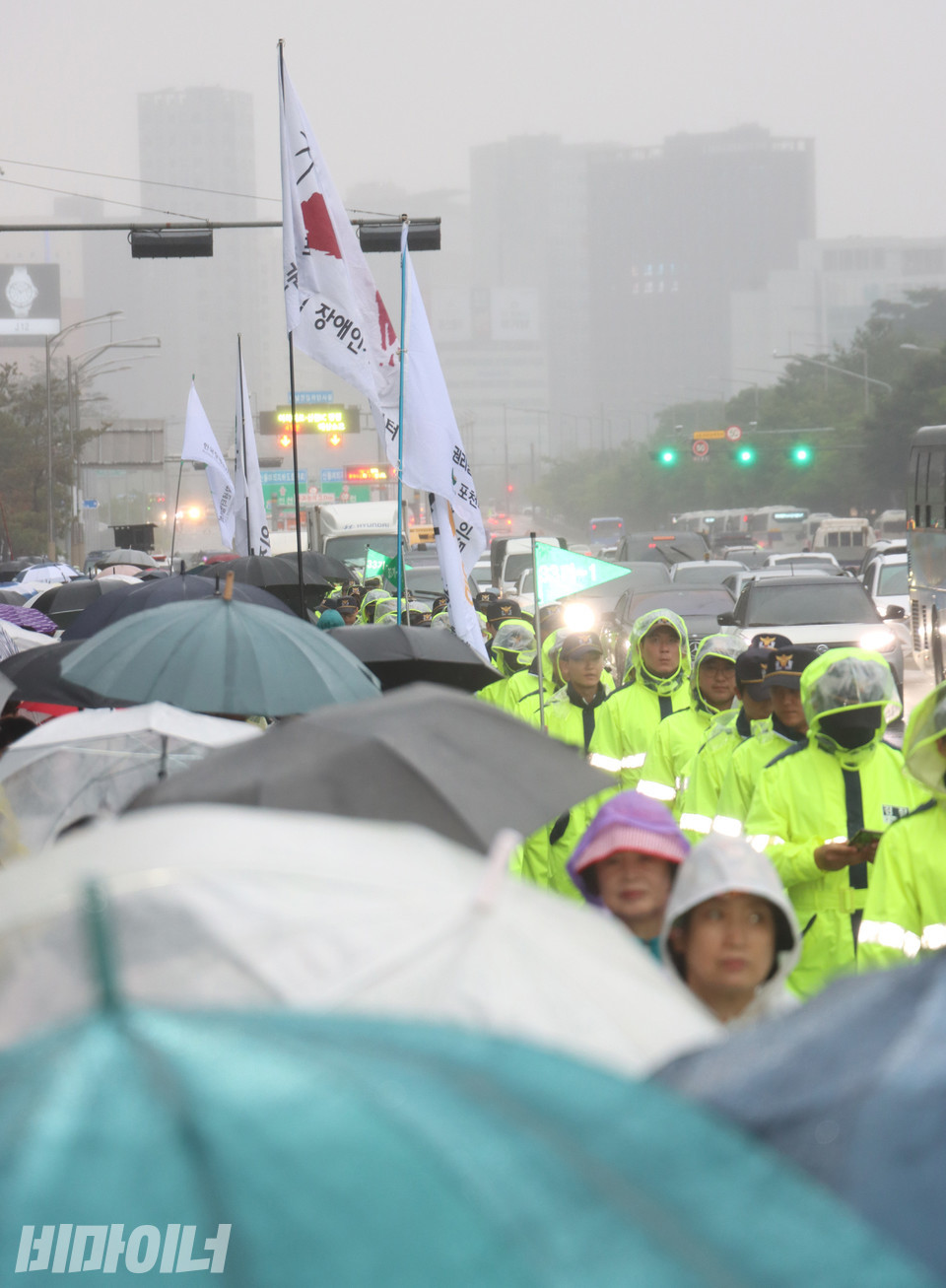 알록달록한 우산과 우비로 마포대교가 가득 찼다. 오른쪽에는 경찰이 보인다. 비로 인해 안개가 자욱하다. 사진 강혜민