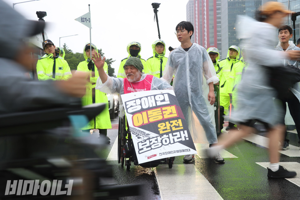 박경석 전장연 상임공동대표가 행진하는 사람들에게 인사하고 있다. 사진 강혜민 
