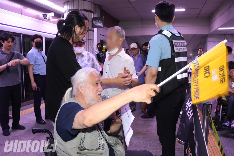 한 시민이 발언하는 박경석 대표에게 다가와 지하철 시위를 그만하라고 항의하고 있다. 우정규 활동가와 서울교통공사 지하철 보안관이 시민을 저지하고 있다. 사진 강혜민