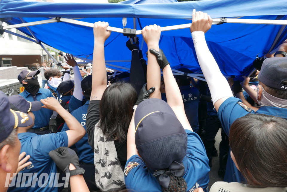 한 경찰이 천막을 지키려는 활동가의 팔을 두 손으로 꽉 잡아 끌어내고 있다. 사진 양유진