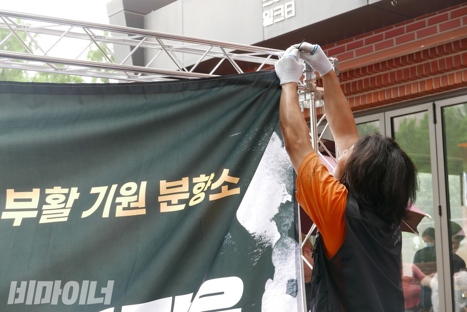 유금문 전국장애인야학협의회 사무국장이 트러스(이동식 무대)에 현수막을 걸고 있다. 사진 양유진