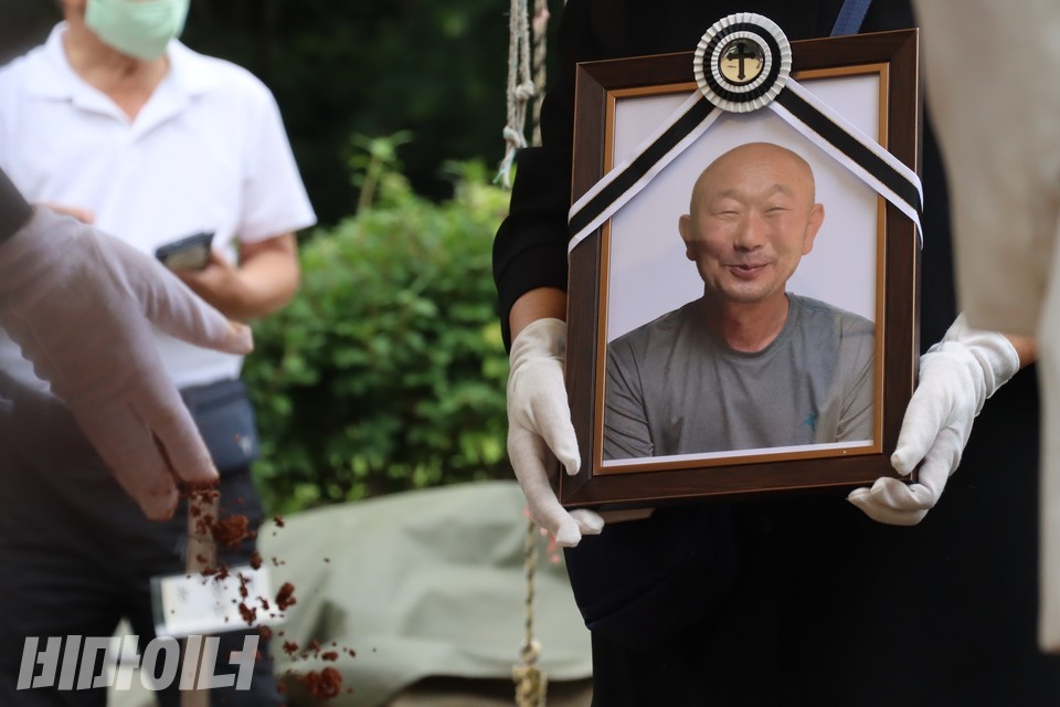 6월 27일, 마사토를 섞은 김정호의 유골이 땅속으로 떨어지고 있다. 오른쪽에는 김정호의 영정이 보인다. 영정을 들고 있는 사람은 김정호의 오랜 연인 오계순이다. 사진 하민지