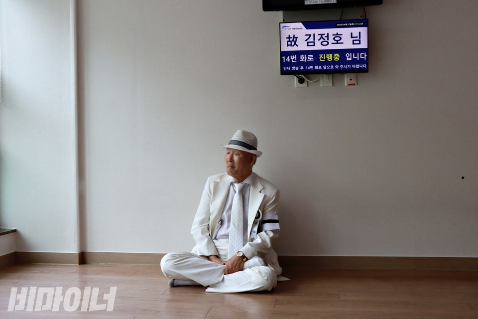 김호태 장례위원장이 앉아 있다. 그의 뒤에 있는 TV 화면에 “고 김정호 님, 14번 화로 진행 중입니다”라고 적혀 있다. 사진 하민지