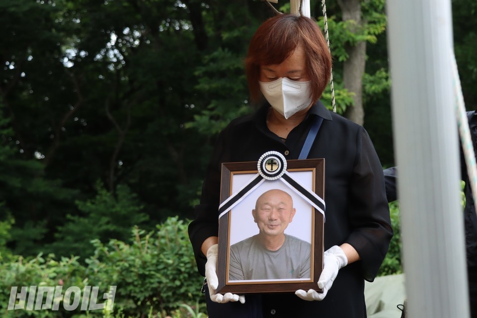 오계순 씨가 김정호 이사장 영정을 들고 고개를 숙이고 있다. 사진 하민지