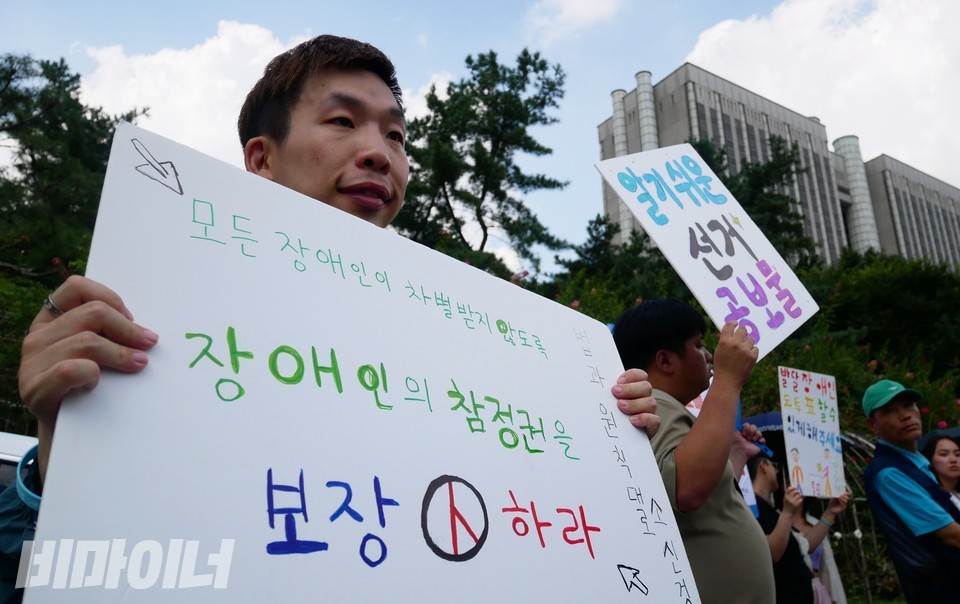 소형민 피플퍼스트서울센터 활동가가 “모든 장애인이 차별받지 않도록 장애인의 참정권을 보장하라”라고 적힌 피켓을 들고 있다. 사진 하민지