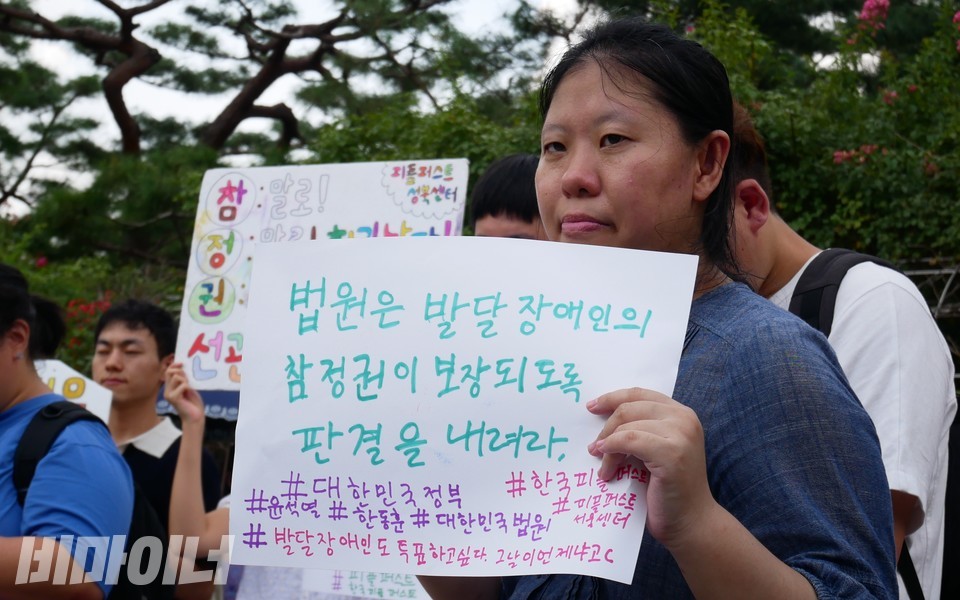 한 활동가가 “법원은 발달장애인의 참정권이 보장되도록 판결을 내려라”라고 적힌 피켓을 들고 있다. 사진 하민지