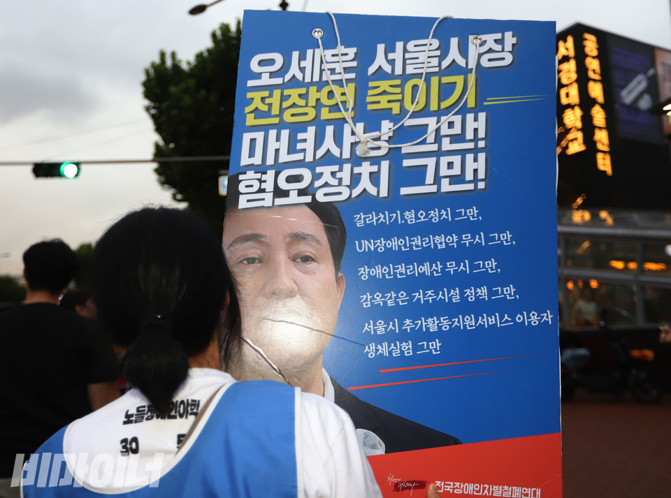 전장연은 결의대회를 마치고 3개 조로 나눠 버스와 지하철을 이용해 서울시청으로 향했다. 한 활동가가 오세훈 서울시장을 규탄하는 피켓을 들고 행진하고 있다. 사진 강혜민