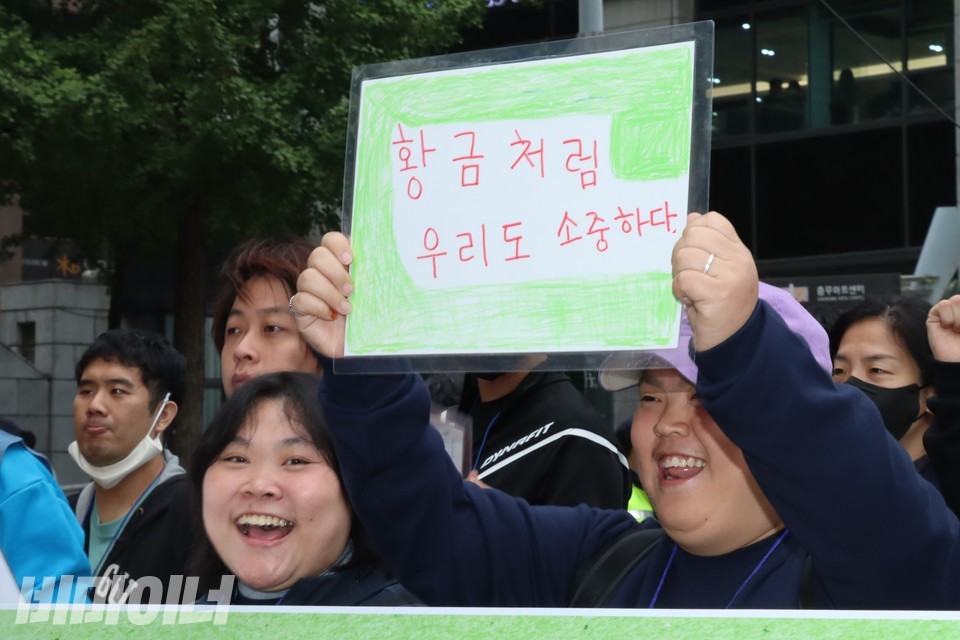 박경인 씨가 “황금처럼 우리도 소중하다”라는 피켓을 들고 환하게 웃으며 행진 중이다. 사진 하민지