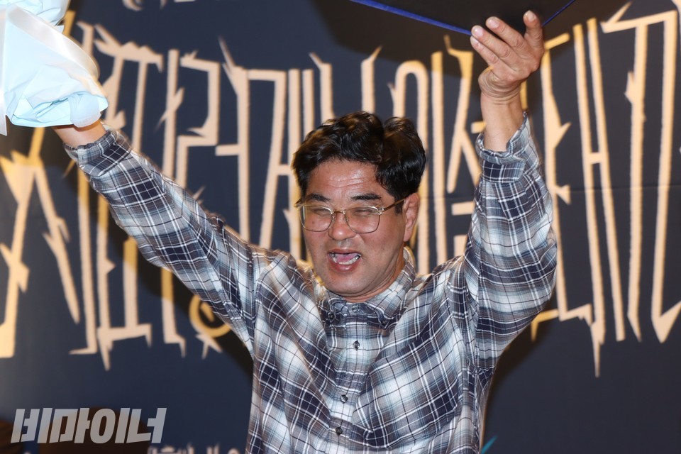 김태완 씨가 양손에 상패와 꽃다발을 들고 만세를 외치고 있다. 사진 하민지