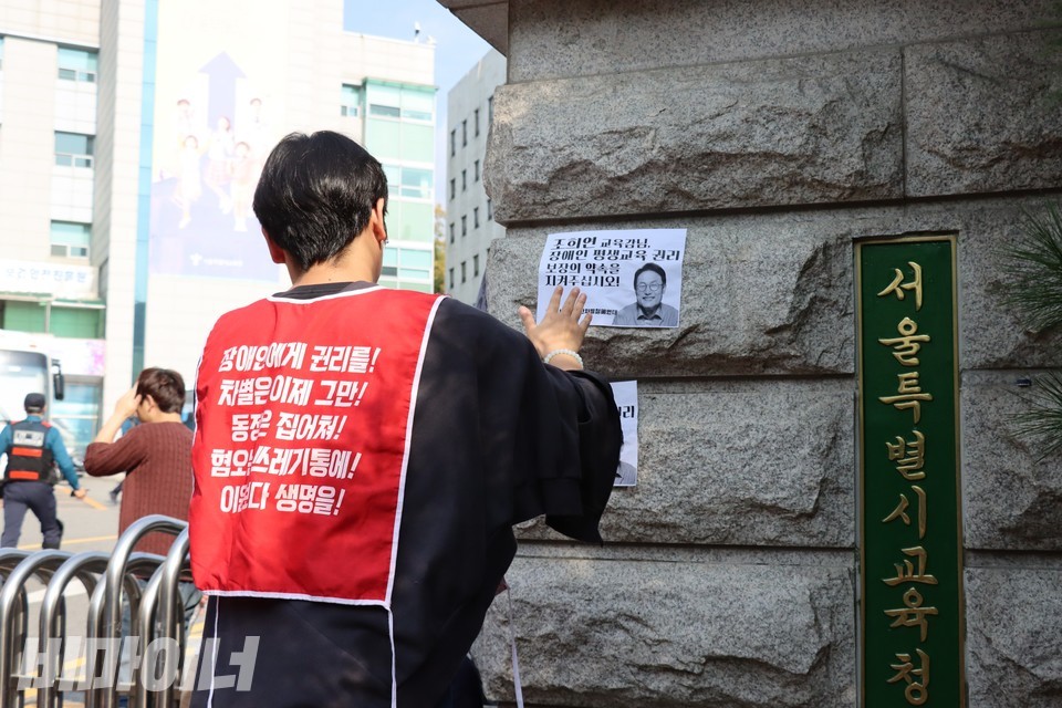찬욱 노들야학 교사가 교육청 정문에 권리스티커를 붙이고 있다. 사진 하민지