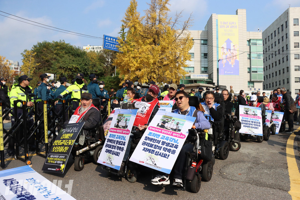 전동휠체어를 탄 장애인들이 “장애인에게 평생교육은 권리입니다! 조희연 교육감님, 장애인의 평생교육 권리보장의 약속을 지켜주십시오!”라고 적힌 피켓을 목에 걸고 구호를 외치고 있다. 사진 하민지