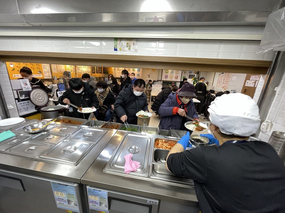 2023년, 들다방 급식 풍경. 사람들이 밥과 반찬을 접시에 담고 있다. 사진 김유미