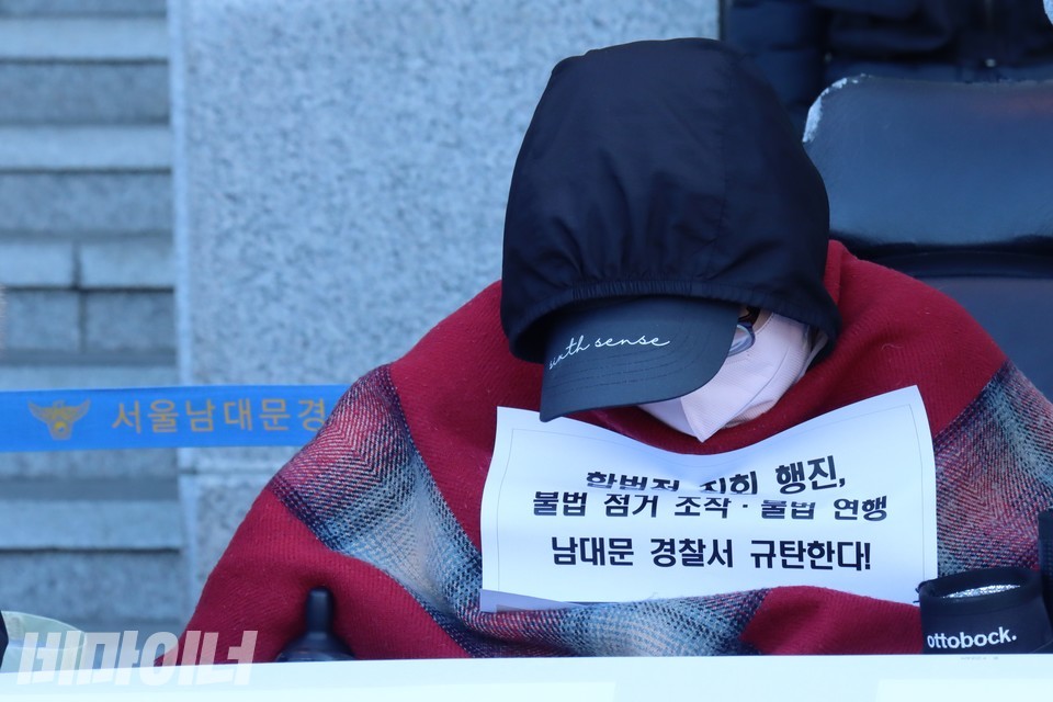 이수미 노들장애인자립생활센터 권익옹호활동가가 남대문경찰서 앞에서 피켓을 들고 고개를 숙이고 있다. 사진 하민지