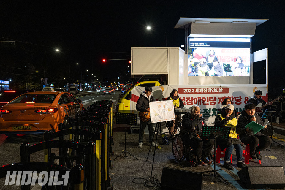 어깨꿈밴드가 공연하고 있다. 그 옆으로 택시가 지나간다. 사진 조진섭