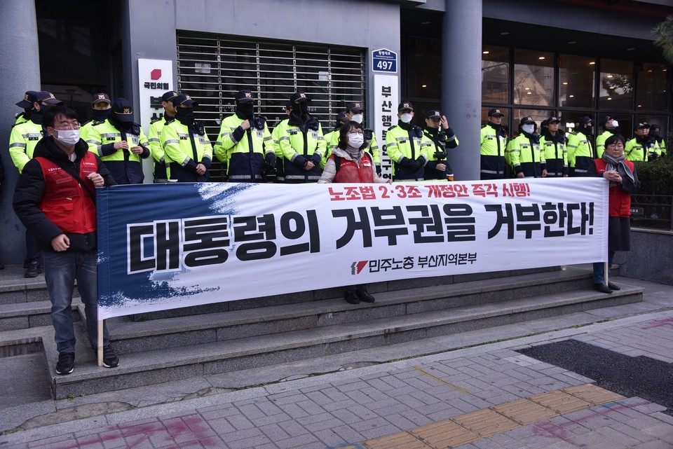 현수막에 “노조법 2·3조 개정안 즉각 시행! 대통령의 거부권을 거부한다!”라고 적혀 있다. 현수막 뒤로 경찰 수십 명이 보인다. 사진 민주노총 부산본부