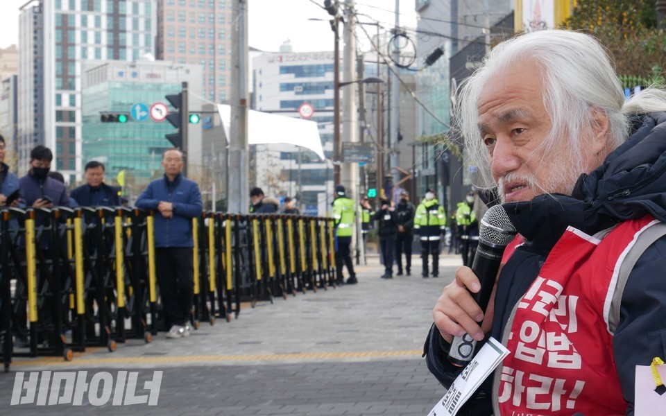 서울교통공사 규탄 기자회견 현장에 있는 울타리. 울타리 너머에서 박경석 전장연 상임공동대표가 발언하고 있다. 사진 하민지