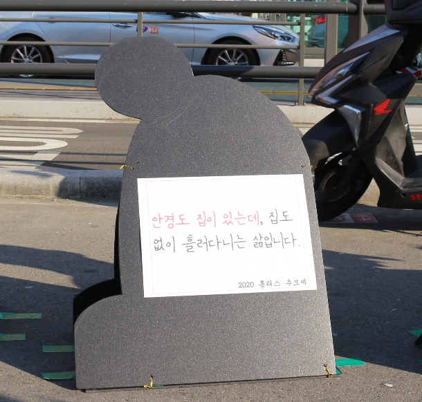 웅크린 사람의 형상을 한 까만색 널빤지에 “안경도 집에 있는데, 집도 없이 흘러 다니는 삶입니다. 2020 홈리스 추모제”라고 적혀 있다. 사진 홈리스추모제공동기획단