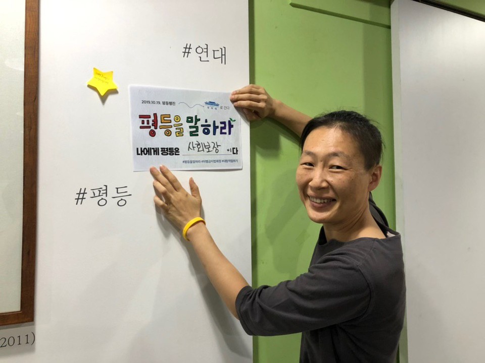 미류 인권운동사랑방 상임활동가가 벽 한 켠에 “평등을 말하라, 나에게 평등은 사회보장이다”라고 적힌 종이를 붙이고 있다. 사진 미류