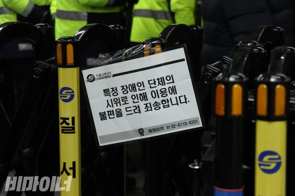 경찰이 설치한 울타리에 서울교통공사가 붙인 안내문. “특정 장애인 단체의 시위로 인해 이용에 불편을 드려 죄송합니다”라고 적혀 있다. 사진 하민지