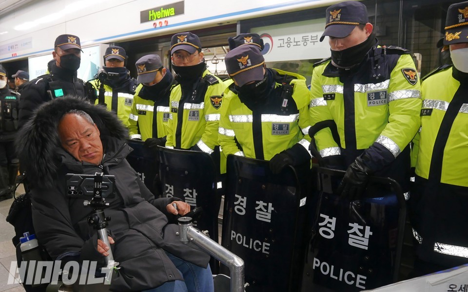 방패로 무장한 경찰 여러 명이 이규식 서울장차연 대표의 지하철 탑승을 막고 있다. 사진 하민지