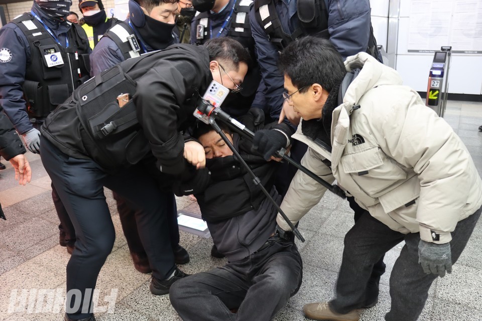 서울교통공사 직원들이 휴대전화와 삼각대를 든 활동가의 팔과 바지춤을 잡고 끌어내고 있다. 사진 하민지