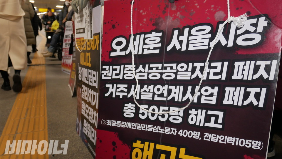 오세훈 서울시장을 규탄하는 피켓들 옆으로 비장애인 승객들이 걸어가고 있다. 사진 하민지