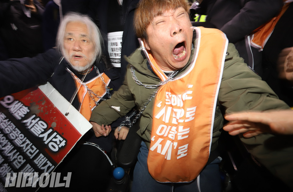 서울교통공사와 직원이 절단기를 들어 보이자 서명석 활동가가 강하게 저항하고 있다. 사진 강혜민