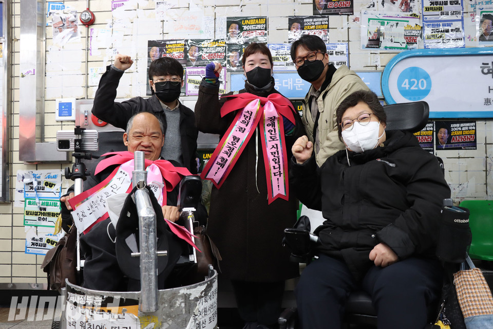 2023년 3월, 혜화역 아침 선전전에 참여한 박채달 씨(가운데)가 장애인 활동가들과 “투쟁”을 외치고 있다. 목에는 “장애인도 시민입니다. 시민의 짐, 혐오정치철폐”라고 적힌 리본을 메고 있다. 사진 강혜민