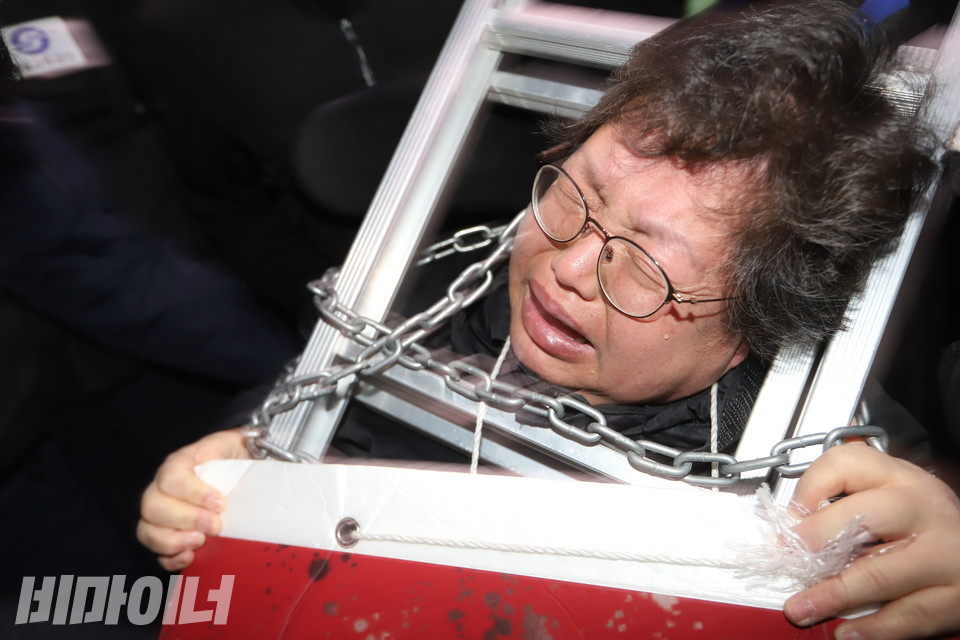 서울교통공사와 경찰이 절단기를 들이대면서 폭력적으로 진압하자, 이형숙 서울장차연 대표가 눈물을 흘리며 소리 지르고 있다. 그의 목에는 사다리와 쇠사슬이 걸려 있다. 공사와 경찰은 기자의 취재를 막으며 강압적으로 끌어냈다. 사진 강혜민