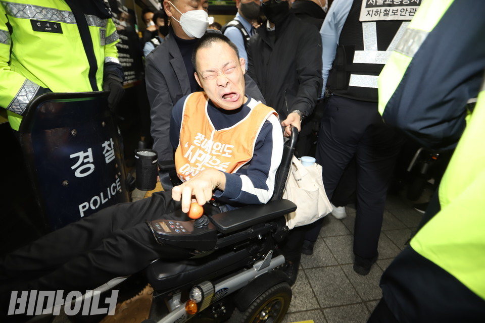 경찰이 전동휠체어 손잡이를 붙잡고 뒤에서 강제로 잡아끌자, 장애인 활동가가 분노하며 항의고 있다. 사진 강혜민