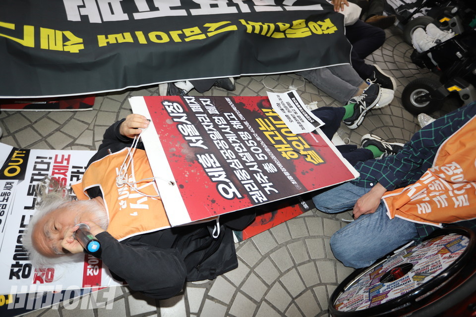 박경석 전장연 상임공동대표가 승강장 바닥에 누운 채 마이크를 손에 쥐고 발언하고 있다. 사진 김소영