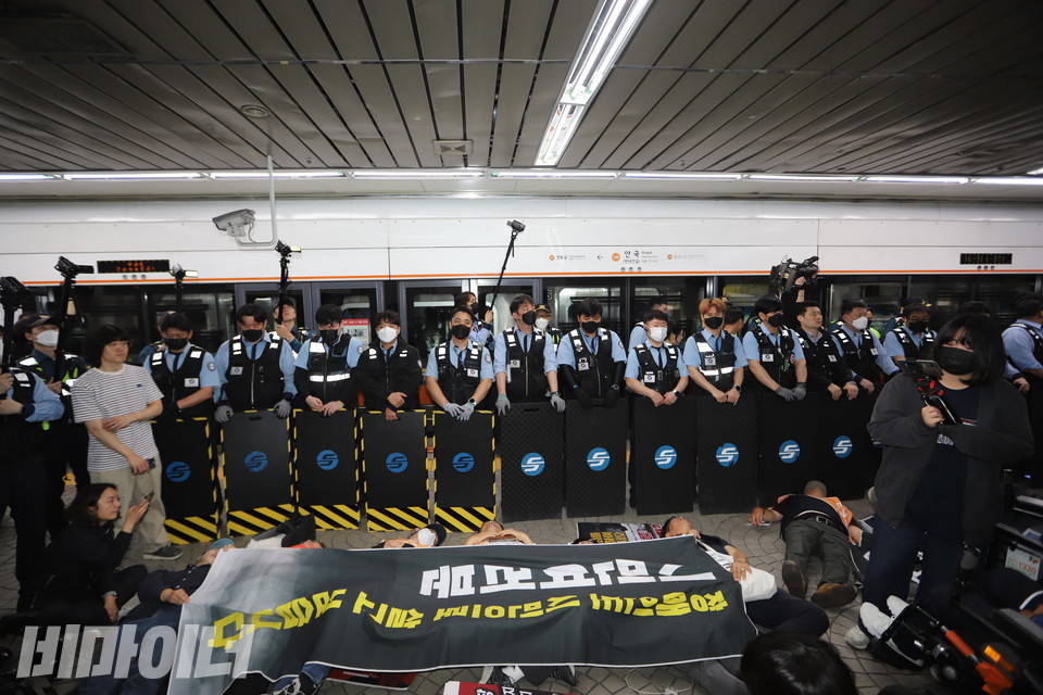 14일 오전, 전장연이 제3차 출근길 지하철 승강장 ‘다이인(die-in) 행동’을 진행하고 있다. 서울교통공사가 방패를 든 채 지하철을 가로막고 있다. 사진 김소영