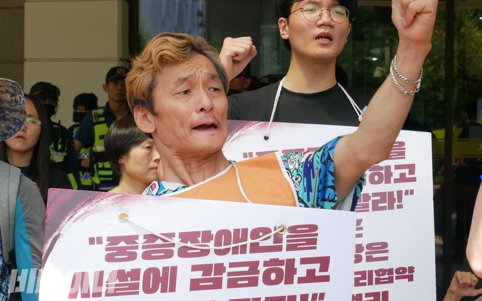 한 활동가가 목에 피켓을 걸고 “투쟁”을 외치고 있다. 사진 하민지