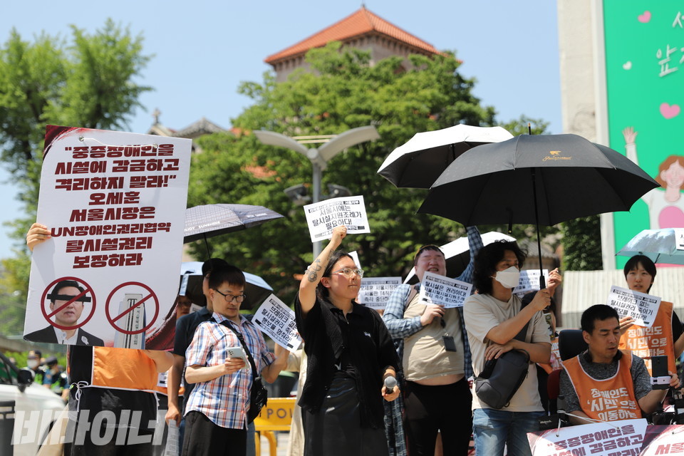 서울시의회의 탈시설지원조례 폐지조례안과 자립생활지원조례 개정안 가결을 규탄하는 기자회견 참가자들이 주먹을 쥔 손을 높이 들며 구호를 외치고 있다. 사진 김소영